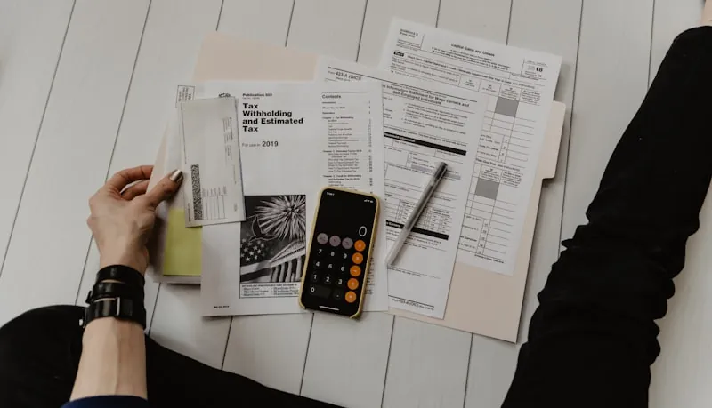 Calculadora, libreta y bolígrafo sobre una mesa de madera